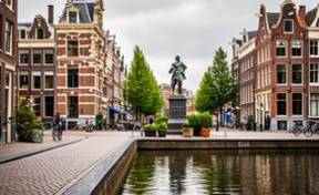 Vista icónica de casas canales y estatua de Rembrandt en Ámsterdam.